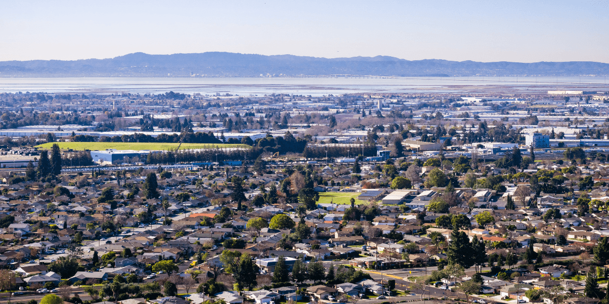 Aerial view of a suburban landscape with greenery and distant mountains in the background