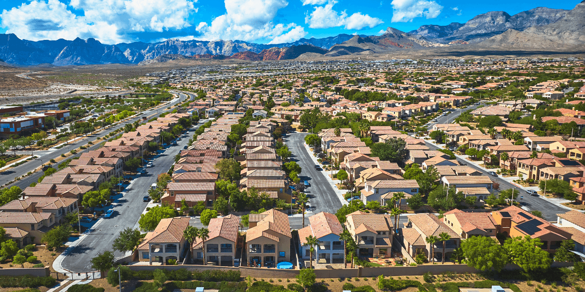 Aerial view of suburban neighborhood with rows of homes and mountains in the background