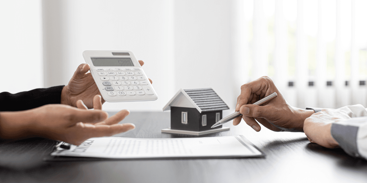 Hands discussing a house model with a calculator and contract on the table