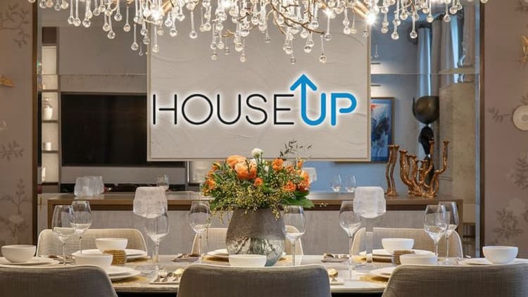 Luxurious dining area featuring modern design with elegant table settings, a floral arrangement, and the houseUP logo.