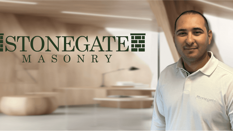 Professional portrait of a man wearing a Stonegate Masonry polo shirt, with a modern office background and the Stonegate Masonry logo displayed prominently.