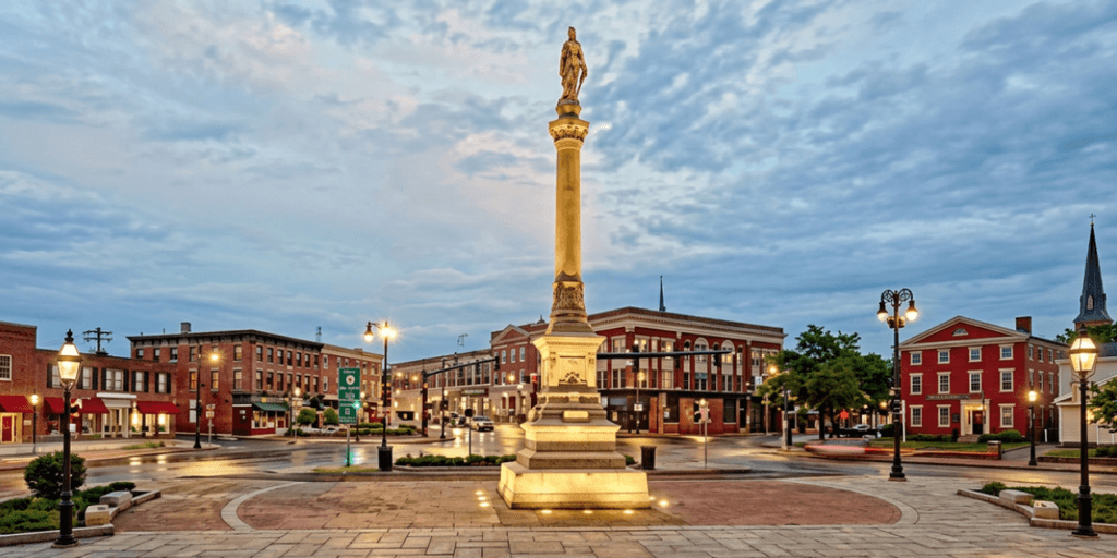 A town square featuring a statue on a pedestal surrounded by historic buildings.