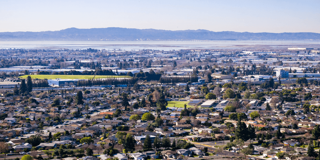 Aerial view of a suburban landscape with greenery and distant mountains in the background