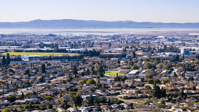 Aerial view of a suburban landscape with greenery and distant mountains in the background