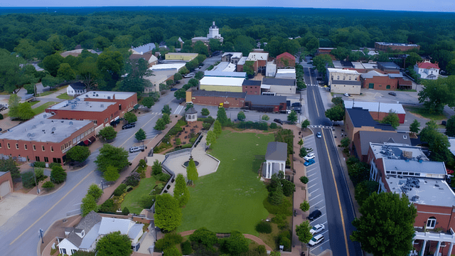 Aerial view of a small town with greenery, buildings, and a central park area