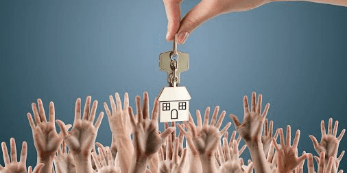 A hand holds house key above multiple reaching hands in a crowd.