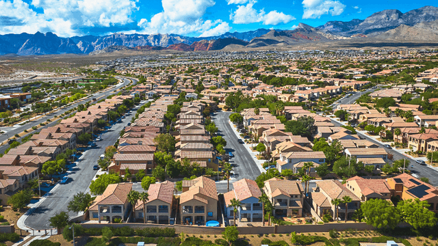 Aerial view of suburban neighborhood with rows of homes and mountains in the background
