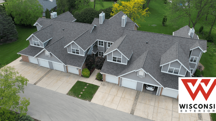 Aerial view of two residential buildings with garages and green landscaping