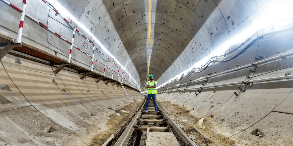 Worker in safety gear stands on tracks inside a tunnel under construction