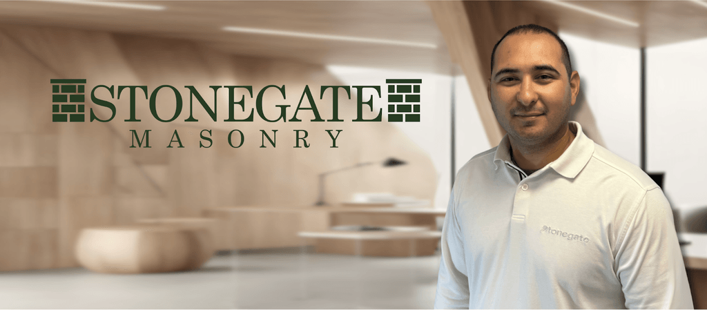 Professional portrait of a man wearing a Stonegate Masonry polo shirt, with a modern office background and the Stonegate Masonry logo displayed prominently.