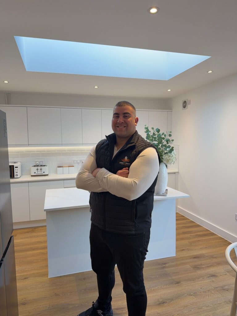Ryan Vye standing in a modern renovated kitchen wearing a Direct Trades branded vest.